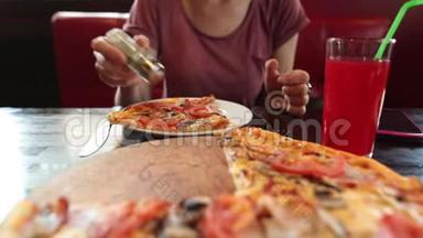 随便的女孩吃一块披萨，用叉子和刀子吃，<strong>坐在餐馆</strong>里。